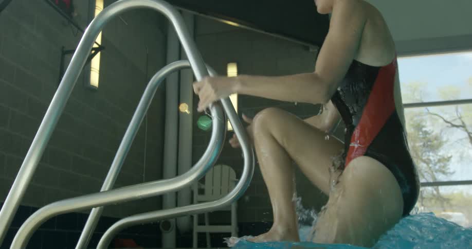 A woman climbs up out of a pool