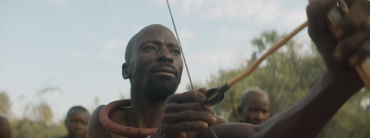 A man is aiming is his bow and arrow