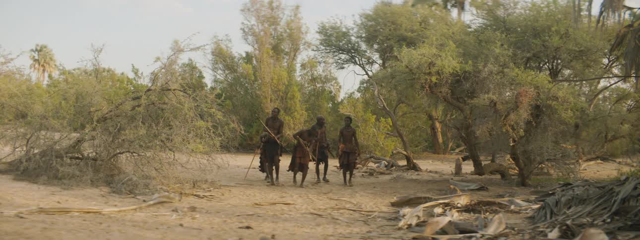 Members of a tribe walk across the land hunting with bows and arrows