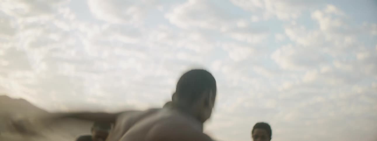 Native teenager dances and spins on the desert sand while four friends clap and cheer him on