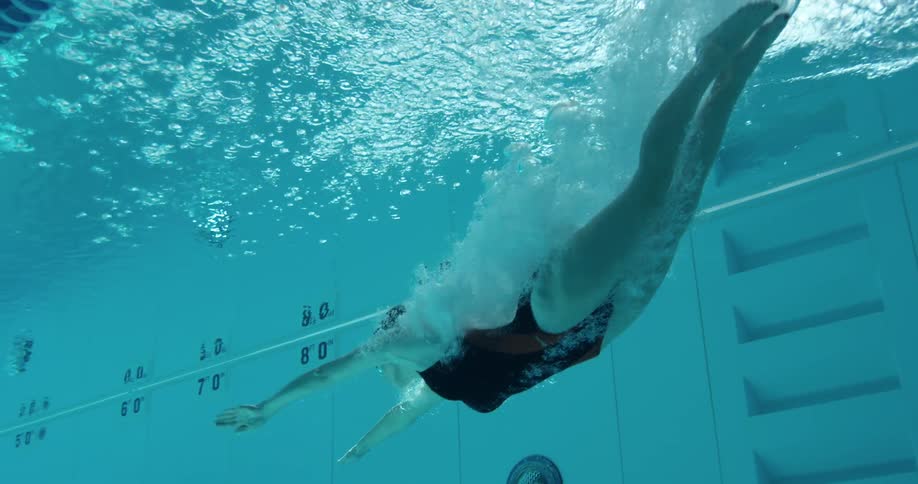 A woman dives into a pool and swims