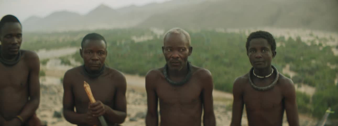 Tribal members standing on top of a hill holding bows and arrows