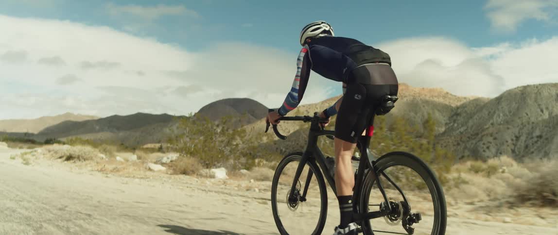 A cyclist is riding on a dirt road through the hills
