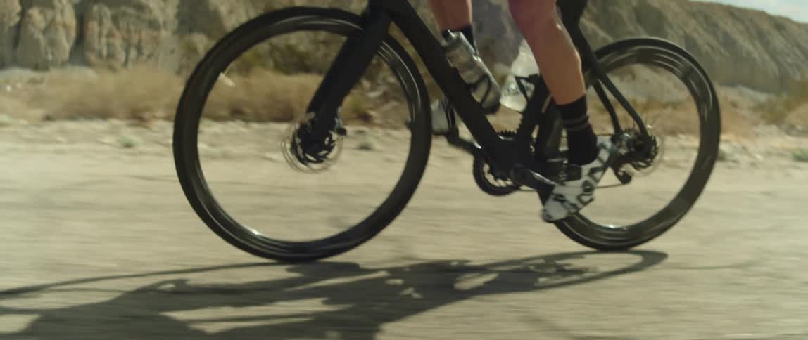 A man rides his bicycle past desert mountains