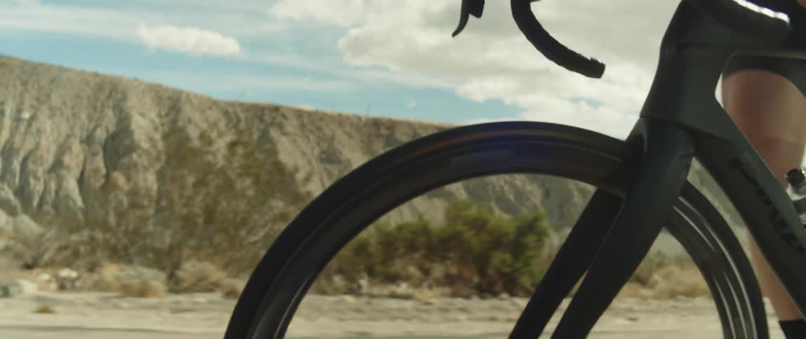 A cyclist rides a bicycle along a road through the countryside during the day
