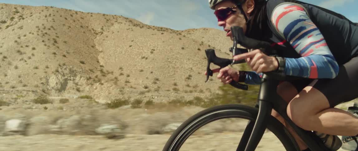 A man riding a bicycle on a desert road in the daytime