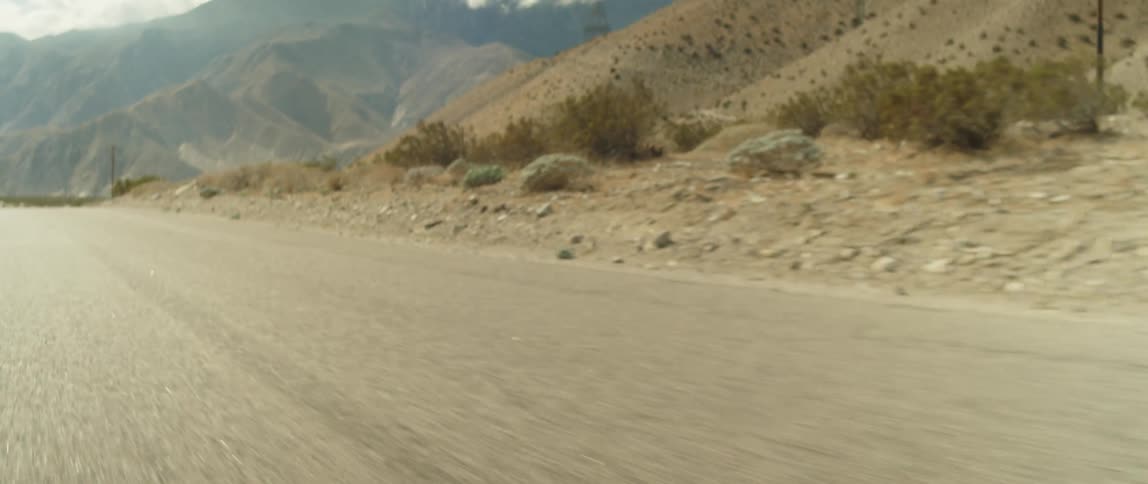 A road cuts through the high desert into bigger mountains