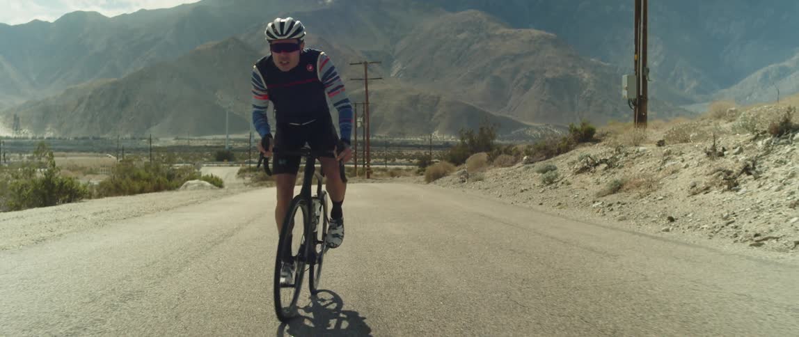 A man rides a bicycle on a rural dirt road