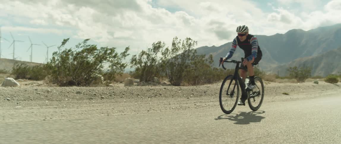 A man bikes past wind turbines