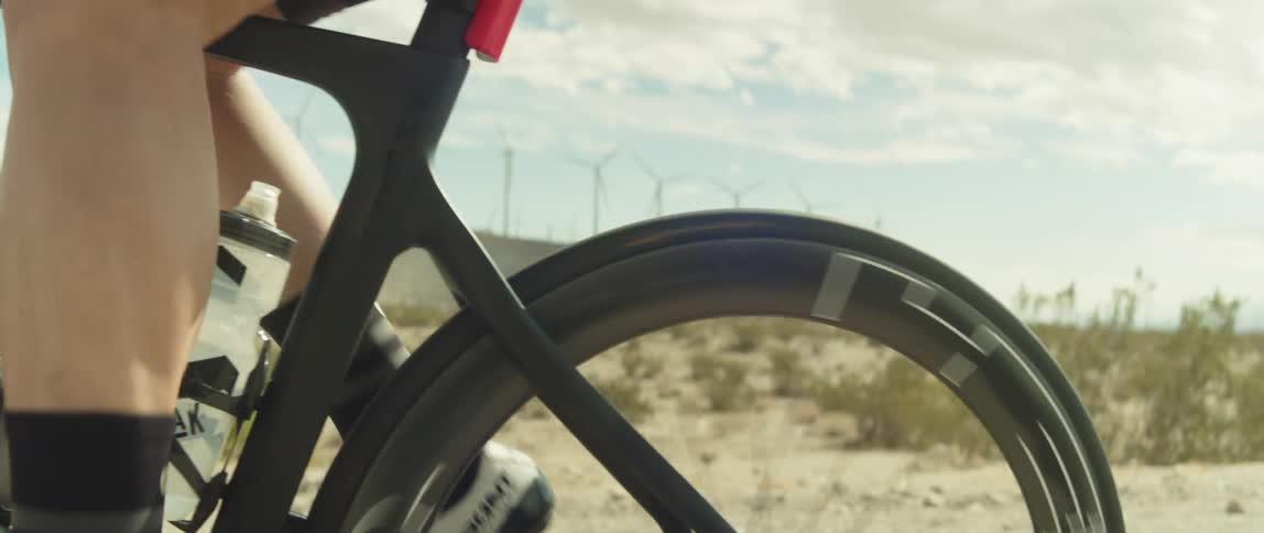 Man rides a bicycle on a desert close to wind turbines