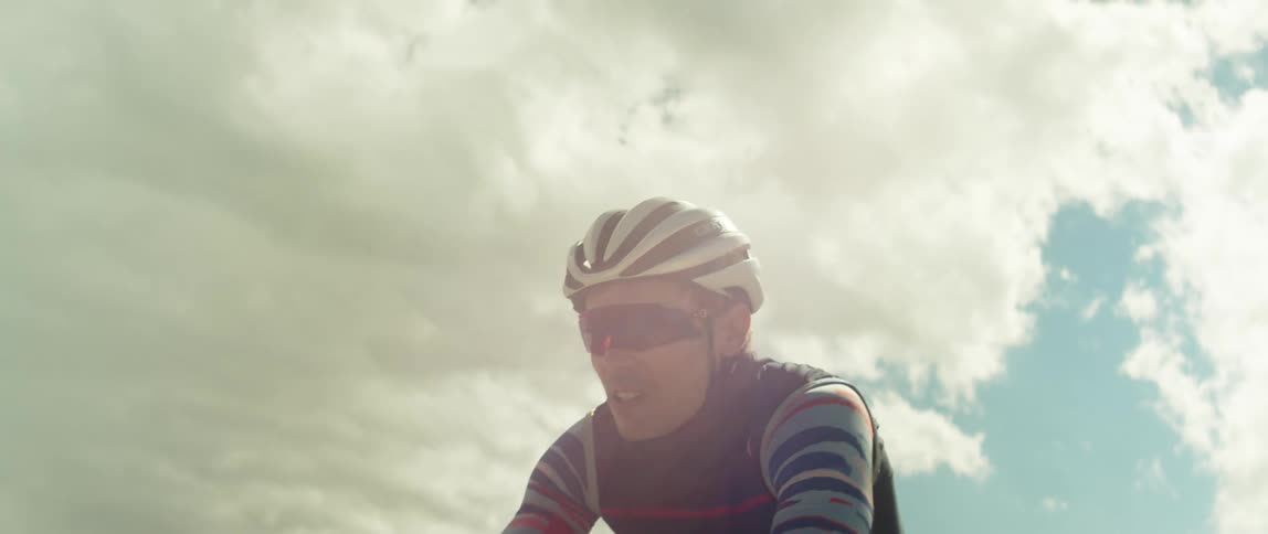 A man in a helmet riding a bicycle outdoors on a cloudy day