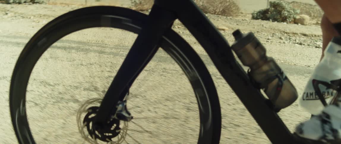 Male cyclists with shorts black socks and white shoes pedals bicycle on country road