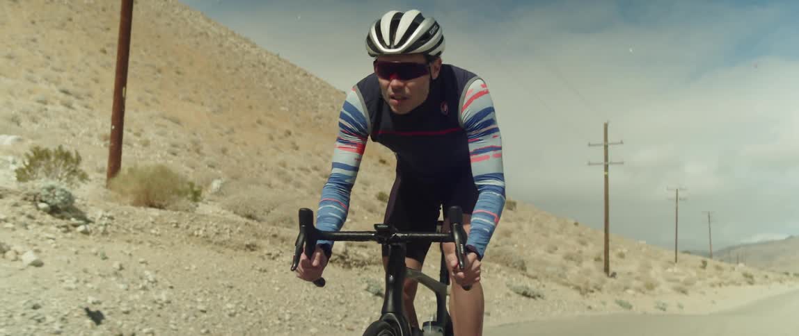 A man pushes to pedal his bike up a desert mountain road