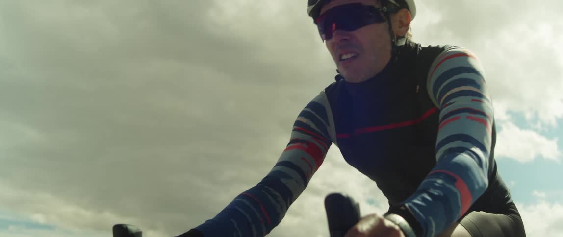 Male cyclist with helmet glasses shorts and jersey shirt cycles on country road