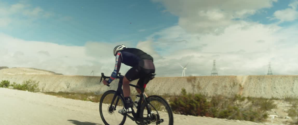 A cyclist pedals hard while cycling along a gravel road in the arid countryside during the day