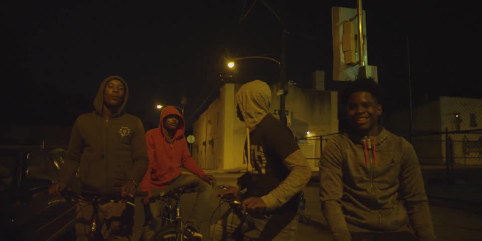 A group of teenagers are on the street at night