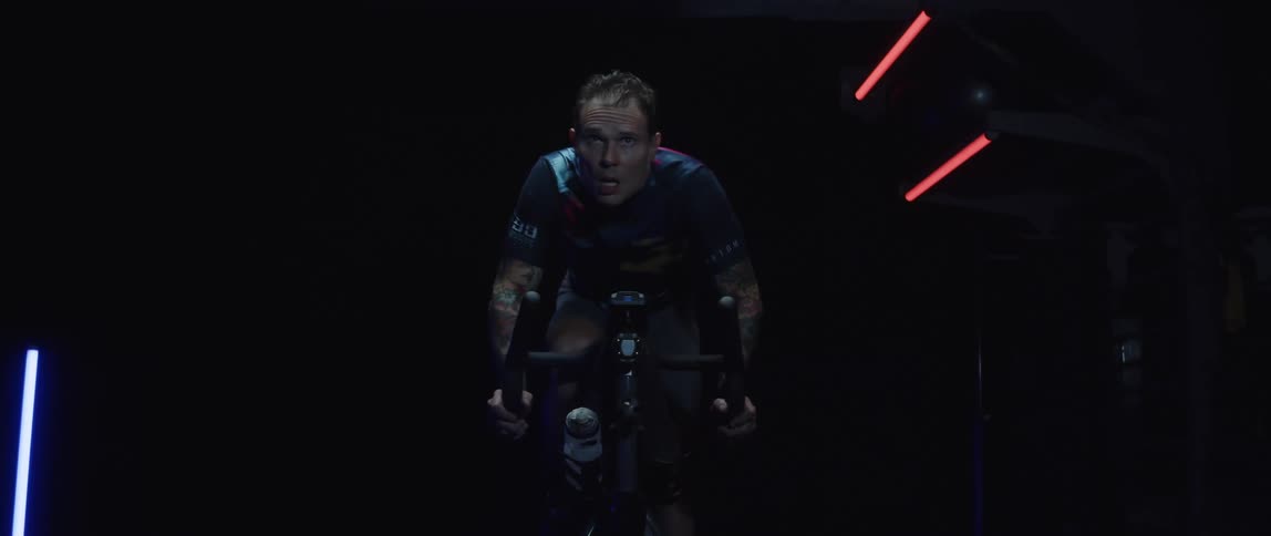 Man pedals exercise bike in dark room