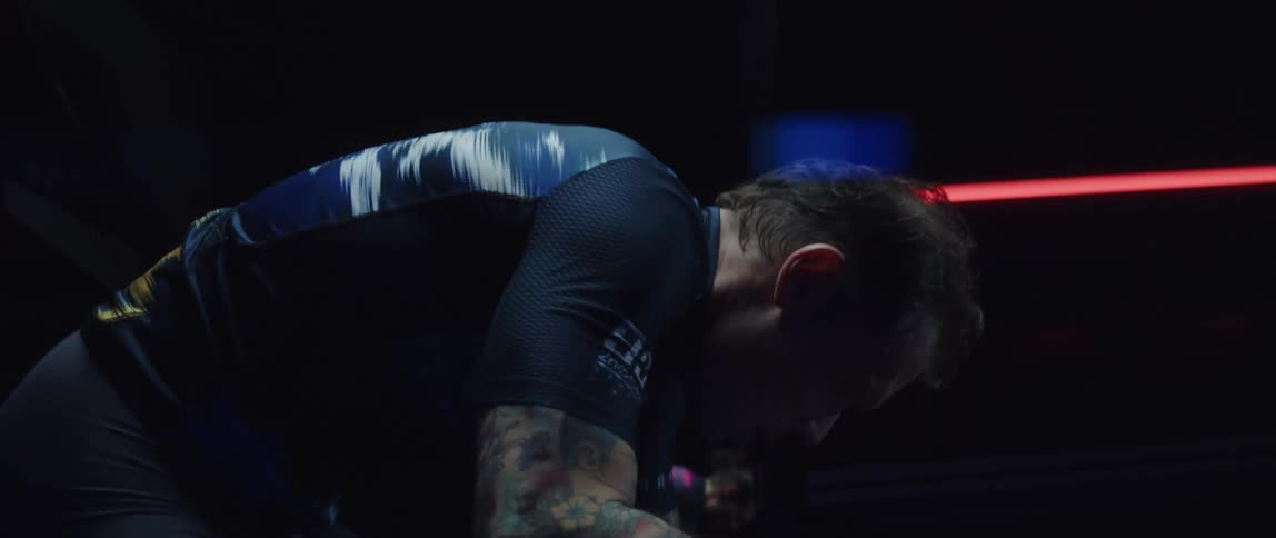 Man pedals on a stationary bike in a dark room