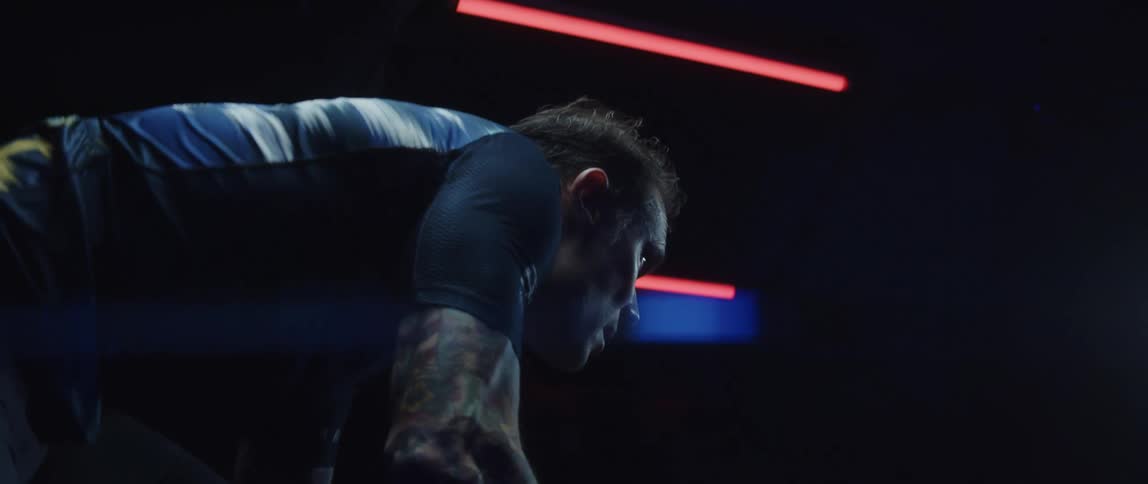 Man pedaling on a static bicycle inside a dimly lit room against a dark background