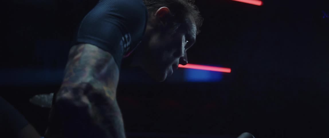 Focused man wearing a cycling jersey exercising on a stationary bike in a dark room