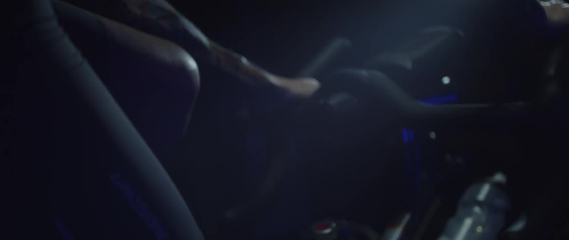Close up of the hands of a man gripping the handlebar of a bicycle while pedaling under blue lights