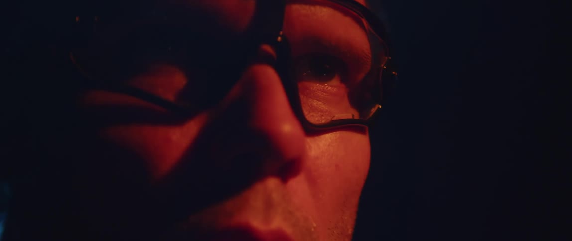 Man wearing glasses in dark area stares