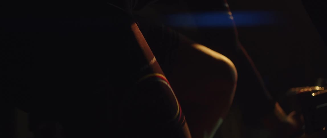 Legs of a man wearing shorts cycling on a stationary bike at a dark room