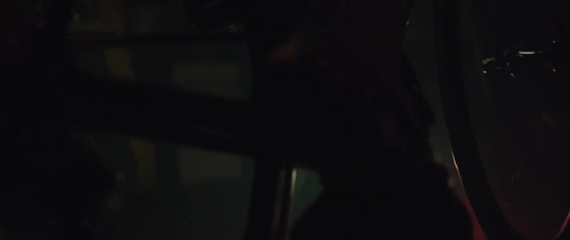 Close up of the gears and pedals of a static bicycle being pedaled inside a dimly lit room