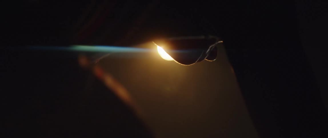 Silhouette of a man pedaling a static bicycle inside a dimly lit room under a spotlight