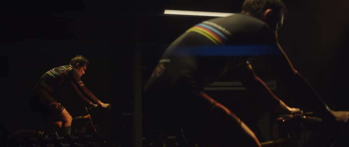 A man riding a stationary bike in a dark room with a mirror