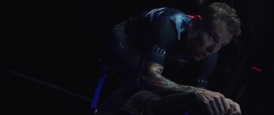 A man riding a stationary bike in a dark room
