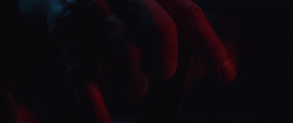 Close up of the hand of a man gripping a bicycle handlebar inside a dimly lit room