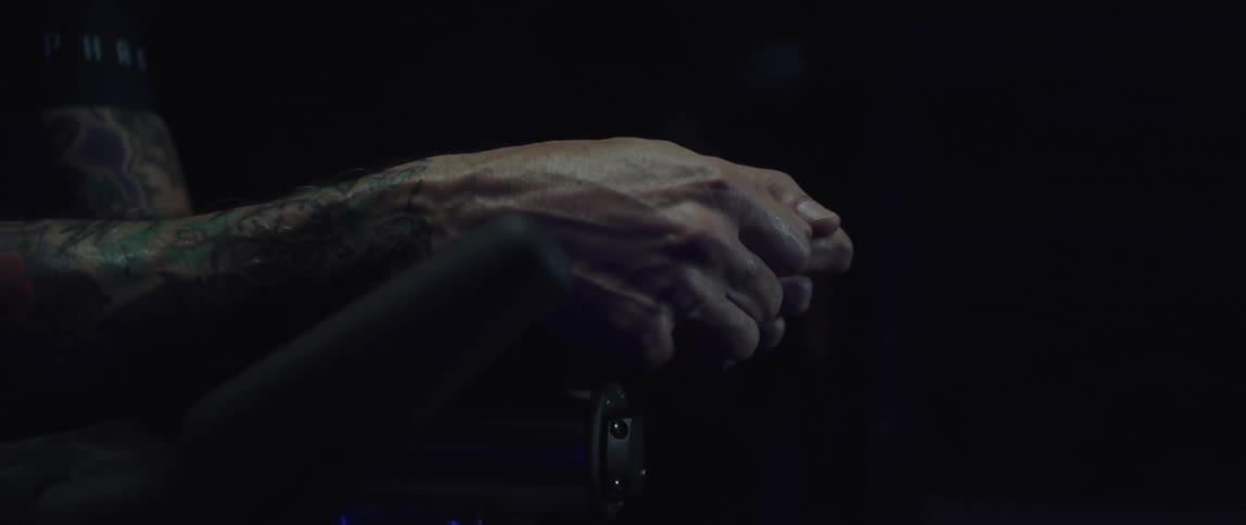Mans hands resting on the handlebar of a stationary bike that he is exercising on