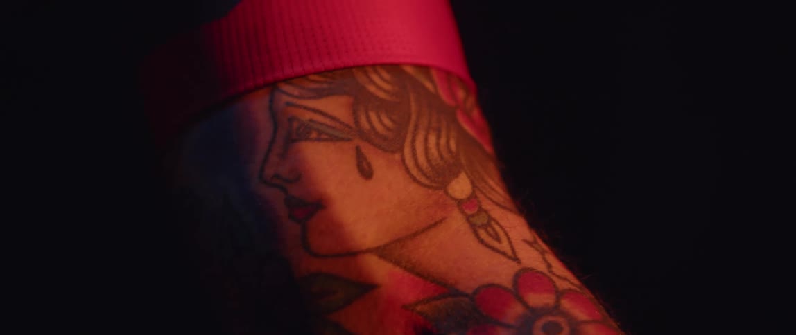 Close up of the tattoo on the arm of a man inside a dimly lit room