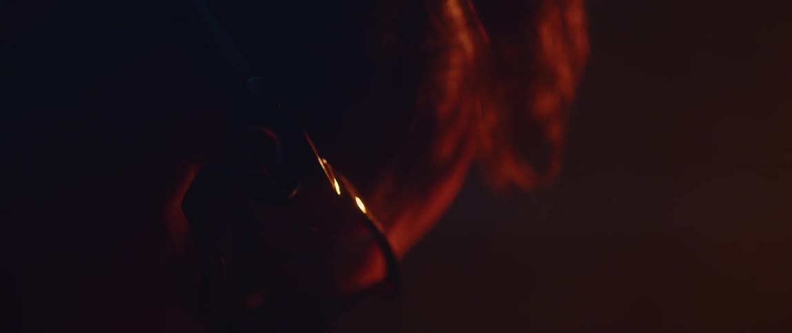 Close up of the profile of a man wearing sunglasses inside a dimly lit room