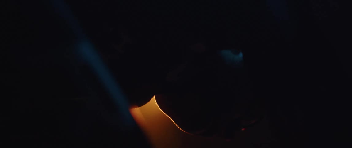 Silhouette of a man pedaling a static bicycle inside a dimly lit room under a spotlight