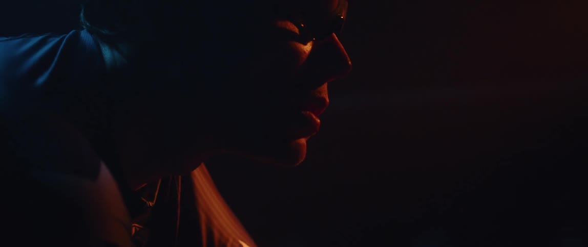 Close up of the face of a man wearing sunglasses inside a dimly lit room