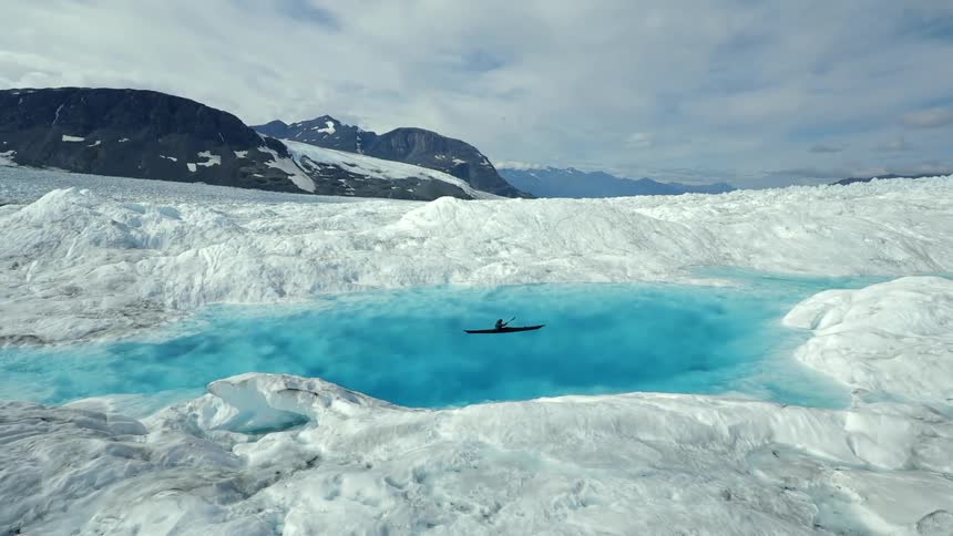 A person kayaks in a blue pool of water