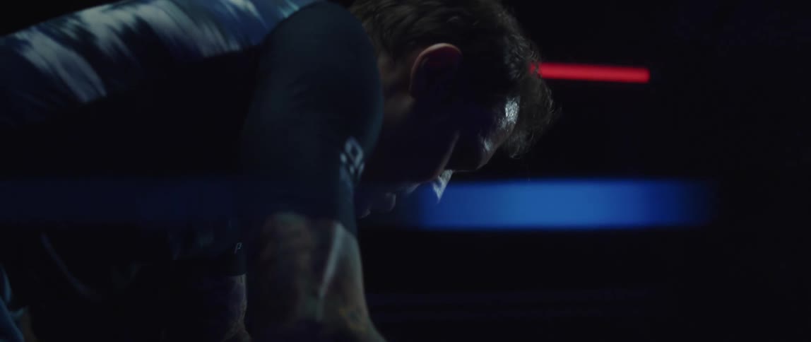 A man is in a very dark room exercising and sweating