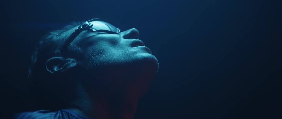 Man wearing protective glasses looks up inside a room under blue lights