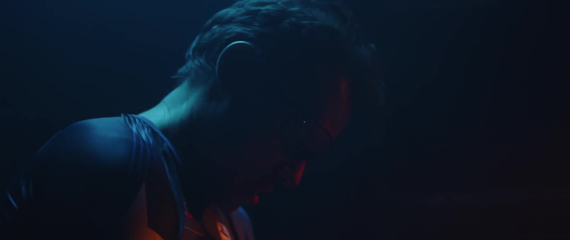 Man tries to catch his breath standing in dark lit by red lighting