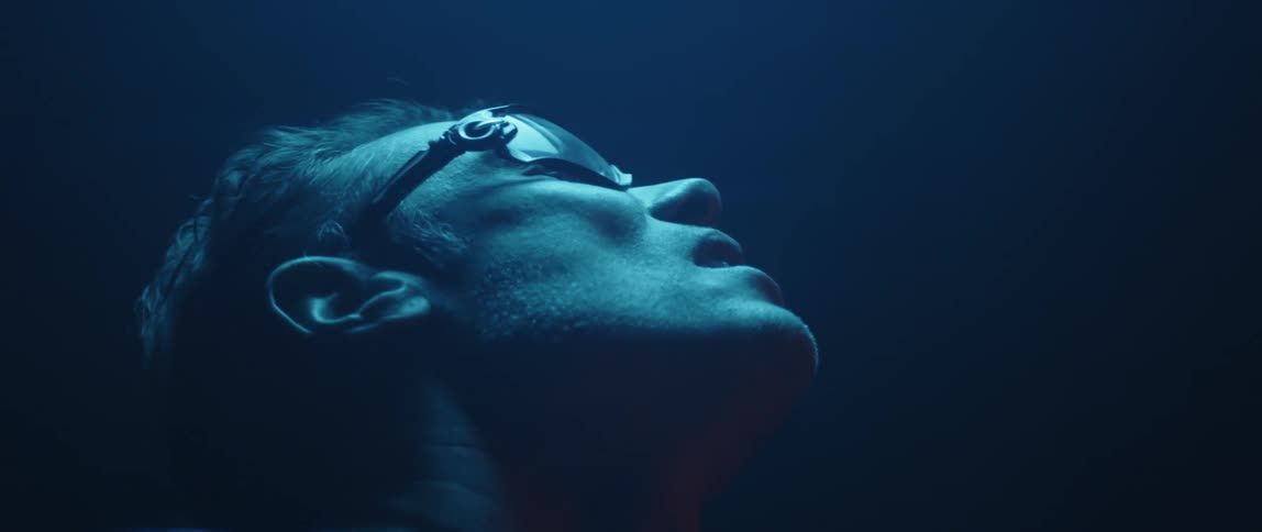 Man wearing protective glasses looks up inside a room under blue lights