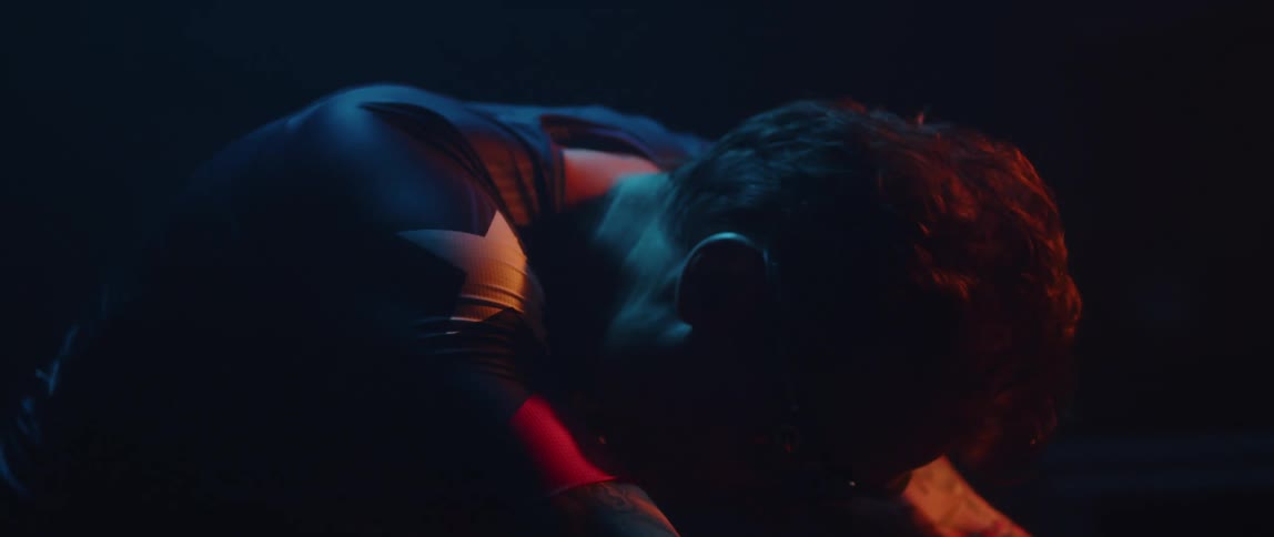 Tired man resting after exercising on a static bicycle on a dimly lit room