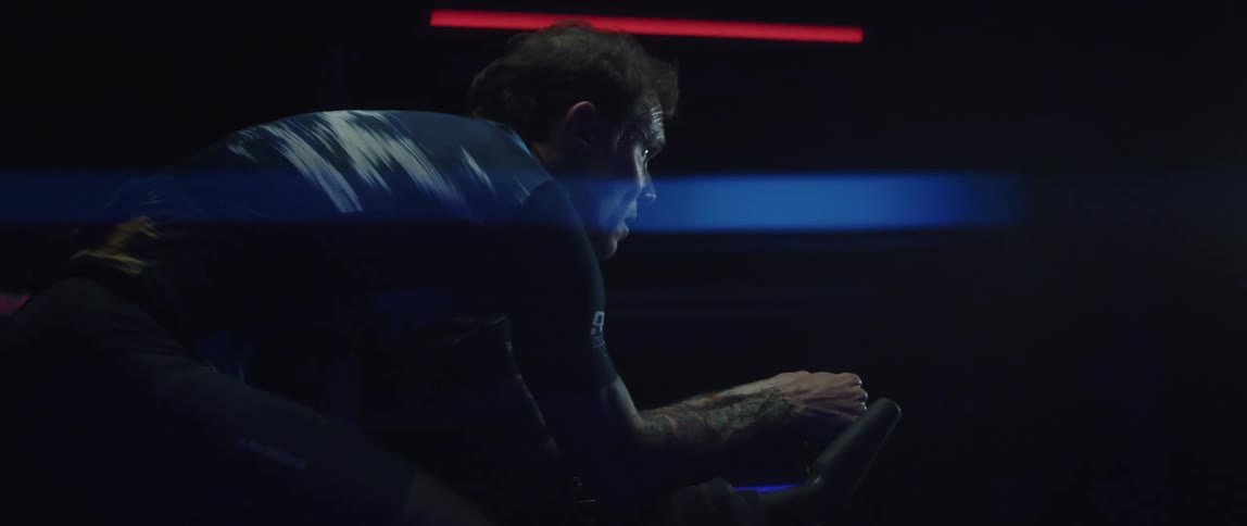 A man exercises on a stationary bicycle in a dark room