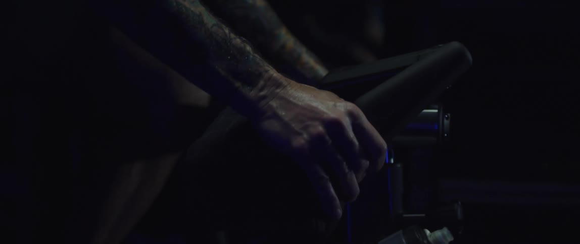 Close up of the hands of a man gripping the handlebar of a bicycle under blue lights