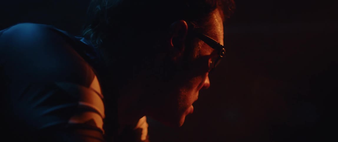 Close up of the face of a man pedaling a static bicycle inside a dimly lit room