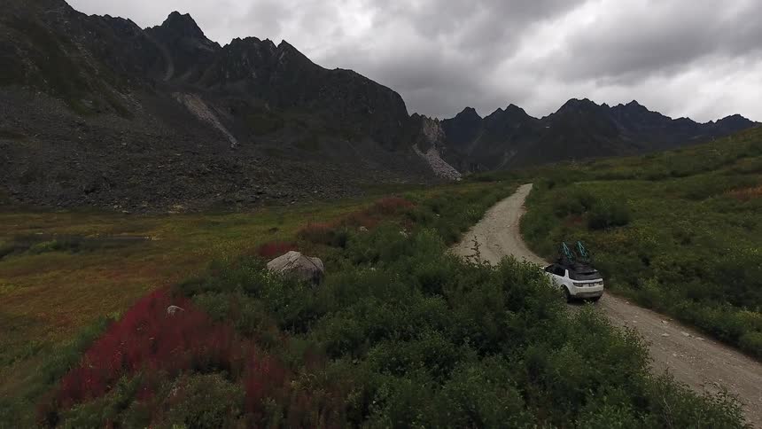 A car drives down a winding road near a mountain
