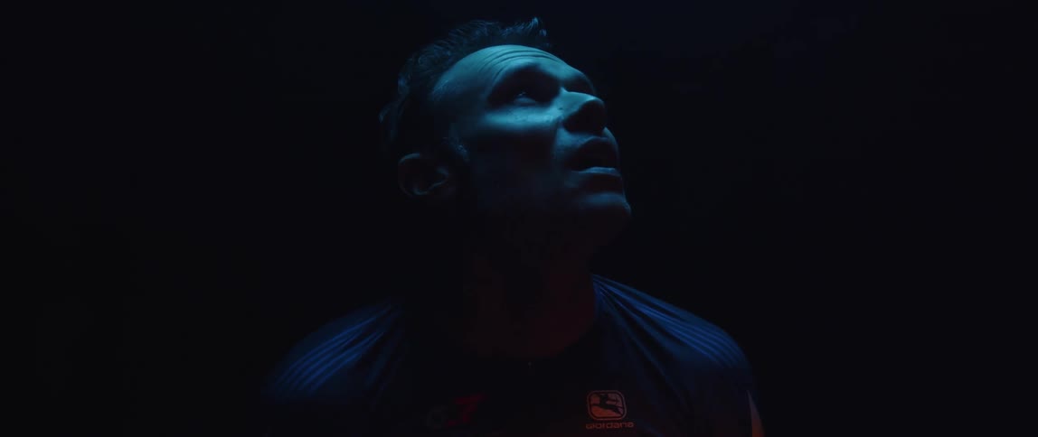 Tatooed man looks up inside a room under blue lights