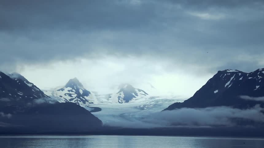 A snowy mountain near a lake on a cloudy day