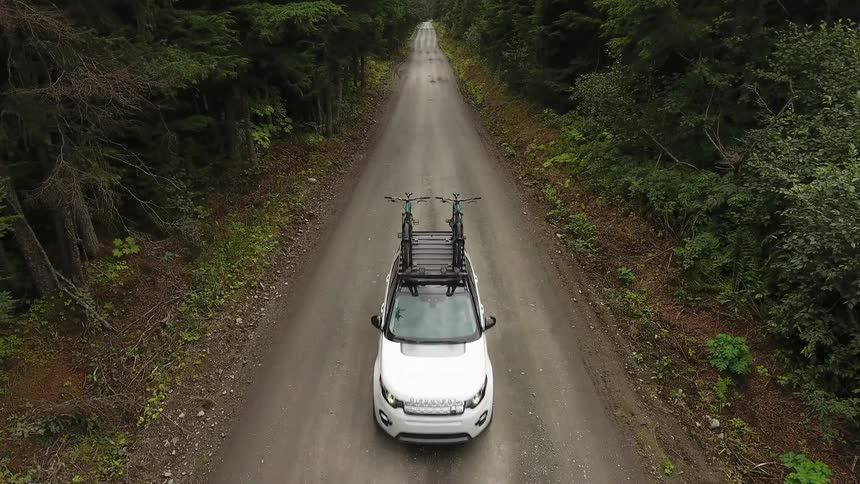 A car with two bikes on it drives down a road
